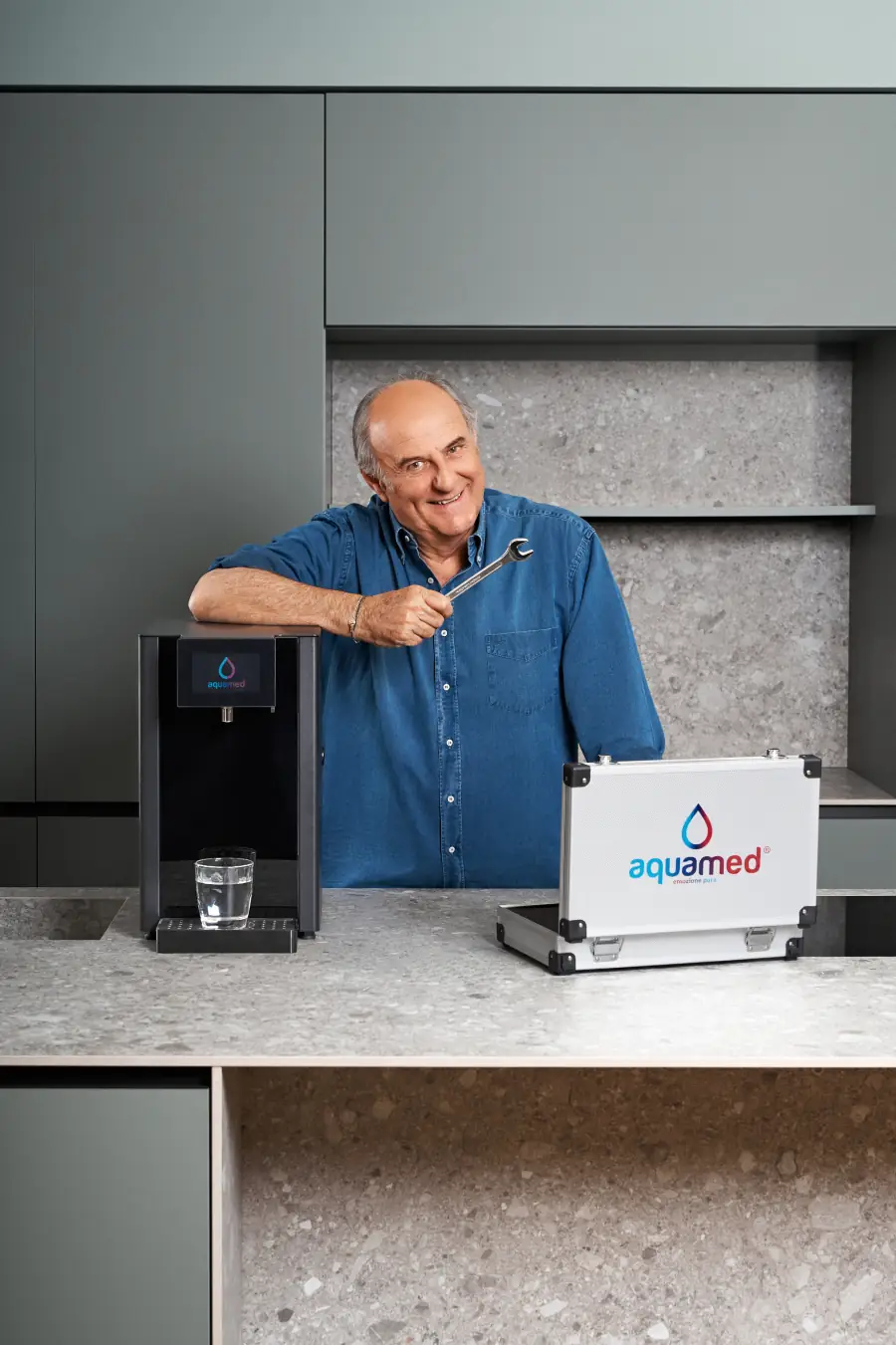 Gerry Scotti in cucina accanto a un depuratore Aquamed e alla valigetta dell’assistenza